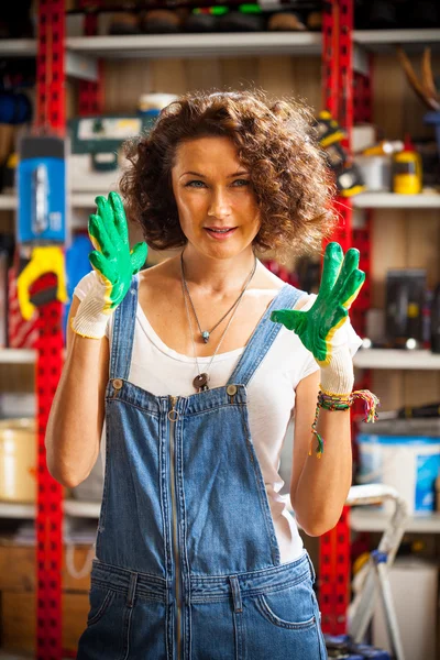 mechanic woman with work gloves on her hands in car repair works
