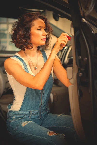 mechanic woman in a blue overalls repair with a screwdriver the