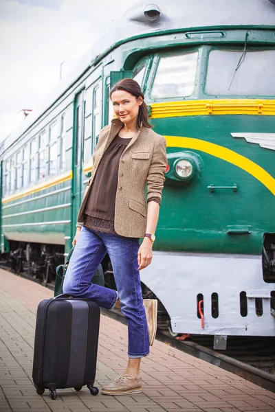 beautiful middle-aged woman with luggage on a railway platform n