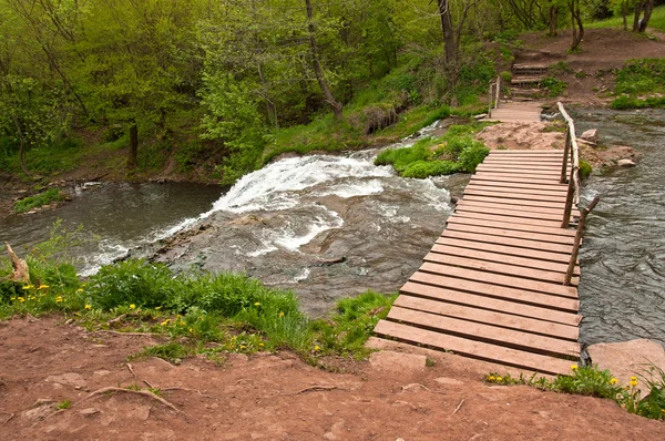 Ponte pedonale in legno attraverso il torrente — Foto Stock