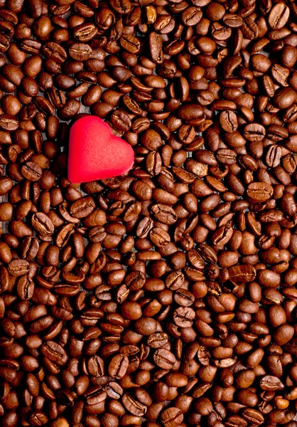 Um coração vermelho em grãos de café — Fotografia de Stock