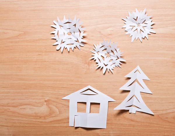Copos de nieve de papel, casa y árbol de Navidad en madera — Foto de Stock