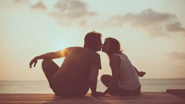 A trópusi napnyugta háttérben csókolózó pár — Stock Fotó