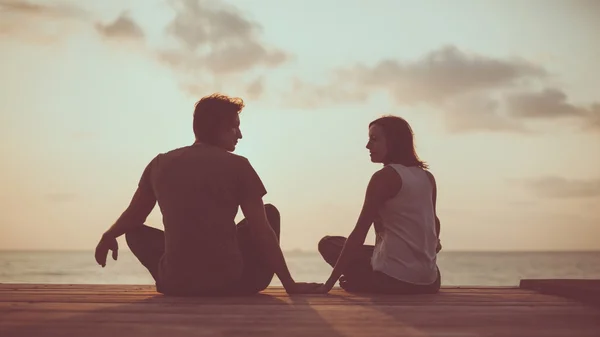 Young couple is doing yoga on the sunrise background. — Stock Photo, Image