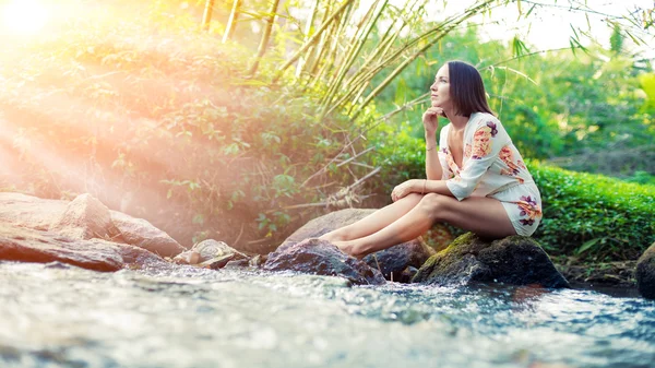 Young woman is sitting on the stone — Stock Photo, Image