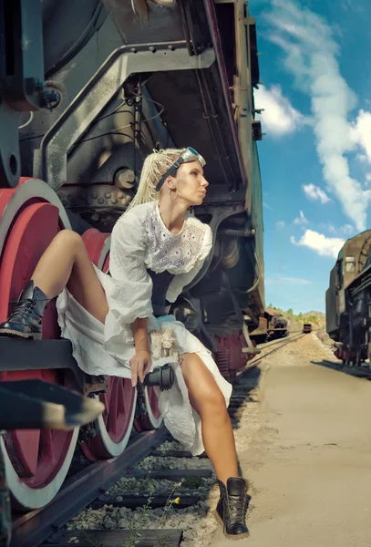 Woman in the vintage dress is sitting on the locomotive's wheel. — Stock Photo, Image