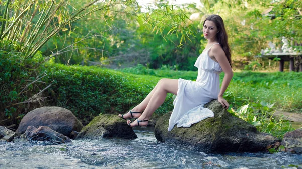 Jovem mulher no vestido branco está sentado na pedra no mi — Fotografia de Stock