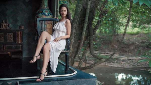 Beautiful woman is sitting on the old wooden chair — Stock Photo, Image