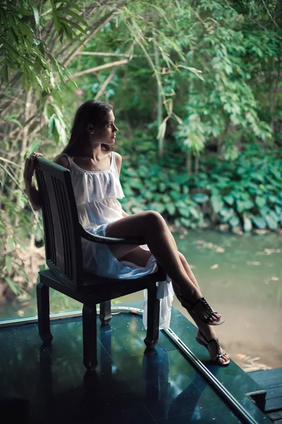 Krásná žena sedí na staré dřevěné židli na tropic — Stock fotografie