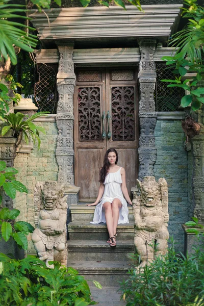 Young woman in white dress is sitting on the stairs of ancient b — Stock Photo, Image