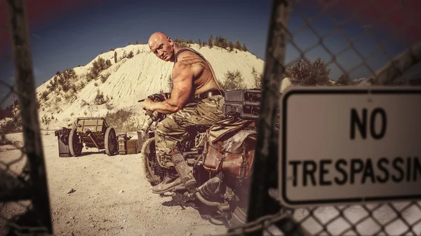 Muscular bald biker on the desert background. — Stock Photo, Image