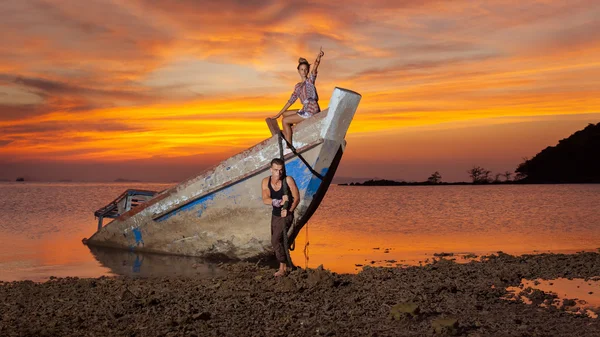 Genç adam sunked tekne, onun kız arkadaşı gösterir çekmek çalışıyor bir — Stok fotoğraf