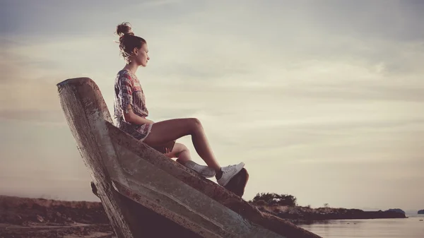 Young woman is sitting on the shipwreck and reading a book. — Stock Photo, Image