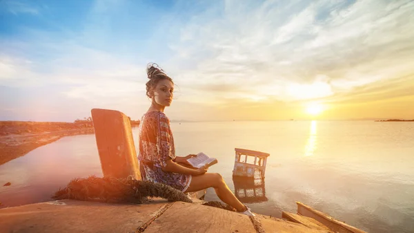 Mujer joven está sentada en el naufragio y leyendo un libro . — Foto de Stock