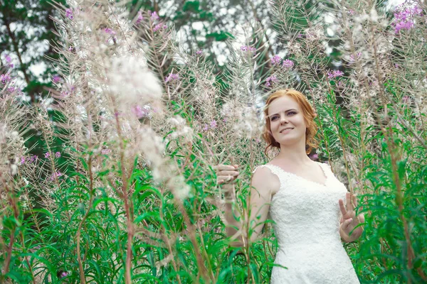 Piękna kobieta w białej sukni wśród magia kwiatów gigant. — Zdjęcie stockowe