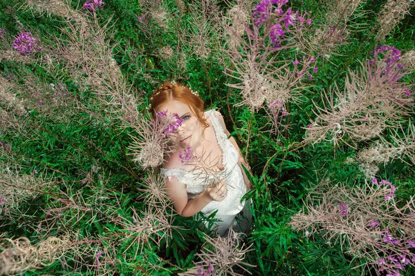 Schöne Frau im weißen Kleid inmitten magischer Riesenblumen. — Stockfoto