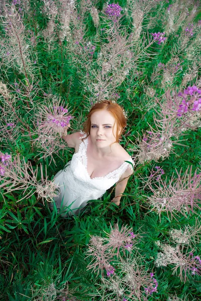 Schöne Frau im weißen Kleid inmitten magischer Riesenblumen. — Stockfoto