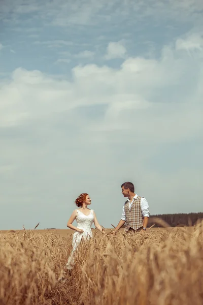 Pasangan bahagia berjalan kaki di latar belakang ladang gandum . — Stok Foto