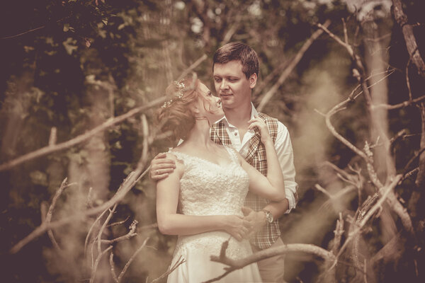 Happy couple is standing on the branch of old tree on the rural background.