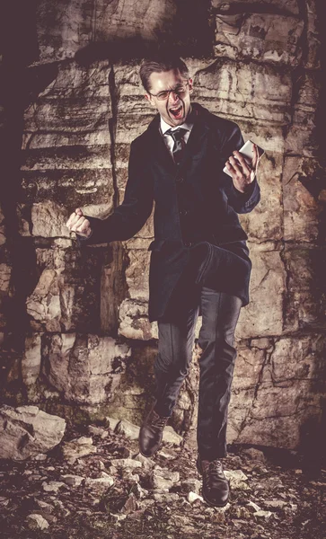 Érzelmi jumping üzletember, azon az éjszakán, sziklák, háttér. — Stock Fotó