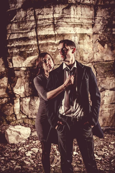 Casal de peolpe bem vestido no fundo rochas escuras . — Fotografia de Stock