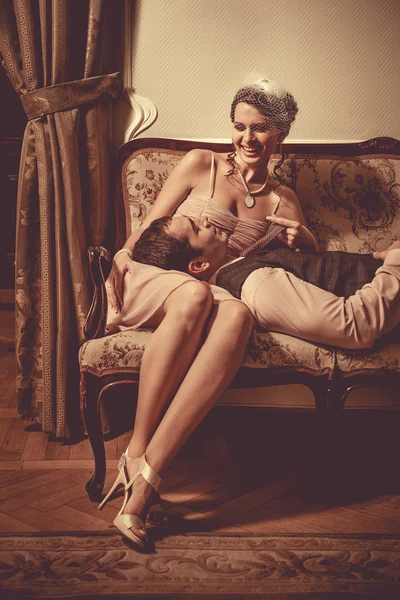 Jovem flertando casal está deitado no sofá. Postagem vintage proces — Fotografia de Stock