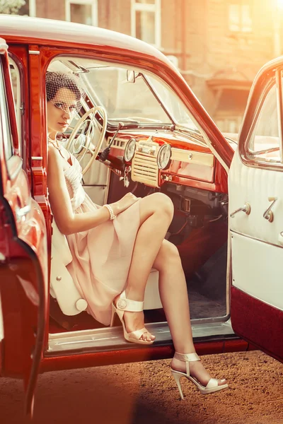 Una mujer guapa con velo está sentada en el auto antiguo. Suma temprana —  Fotos de Stock