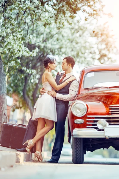Hübsches Paar macht einen Scherz auf seinem roten Auto. — Stockfoto