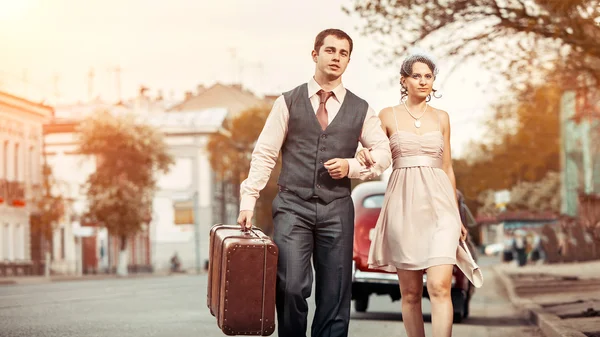 Bastante pareja caminando con la maleta en la parte posterior del coche vintage — Foto de Stock