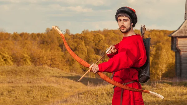 Russian archer with the wooden bow in traditional red suit and f — Stock Photo, Image