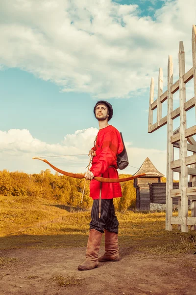 Russischer Bogenschütze mit Holzschleife in traditionellem roten Anzug und F — Stockfoto