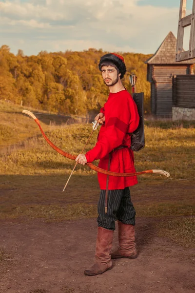 Russian archer with the wooden bow in traditional red suit and f — Stock Photo, Image