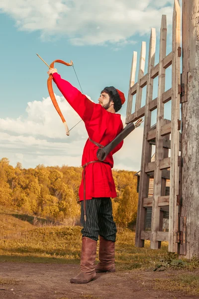 Russian archer with the wooden bow in traditional red suit and f — Stock Photo, Image