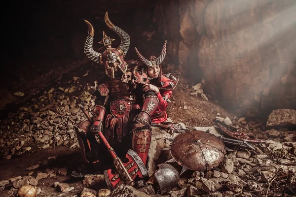 Couple of knights in armor with axe. Catacombs on the background — Stock Photo, Image