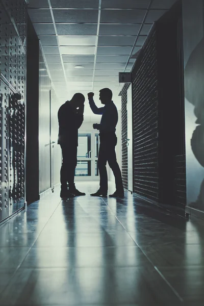 Twee zakenmannen hebben een emotioneel gesprek in een half-donker gang. — Stockfoto