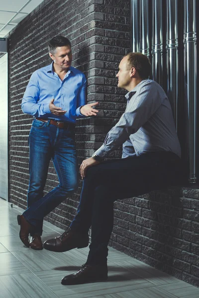 Два бізнесмени розмовляють в напівтемному коридорі . — стокове фото