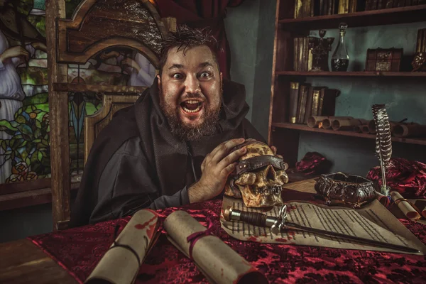 Karanlık odada defada Ortaçağ şişman keşiş gülümseyen.