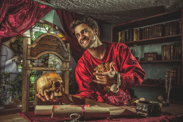 Sorrindo grandeza medieval está apontando para o crânio na mão . — Fotografia de Stock