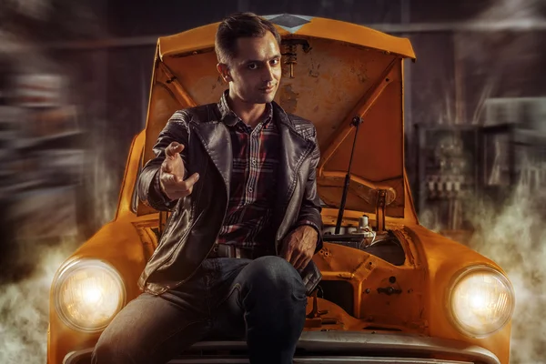 Smart driver is sitting on his old car in the garage and pointin — Stock Photo, Image