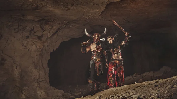 Couple of vikings in armor with swords. Catacombs on the backgro — Stock Photo, Image