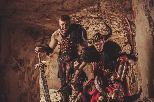 Shouting knights in armor with sword and axe. Catacombs on the b — Stock Photo, Image