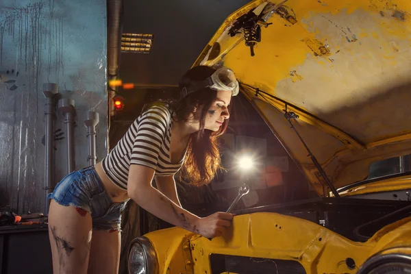 Woman mechanic in sexy shirts is repairing an old car with the w — Stock Photo, Image