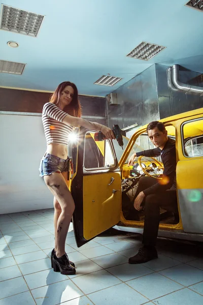 Mulher mecânica em camisas sensuais com o proprietário de um carro velho ar — Fotografia de Stock