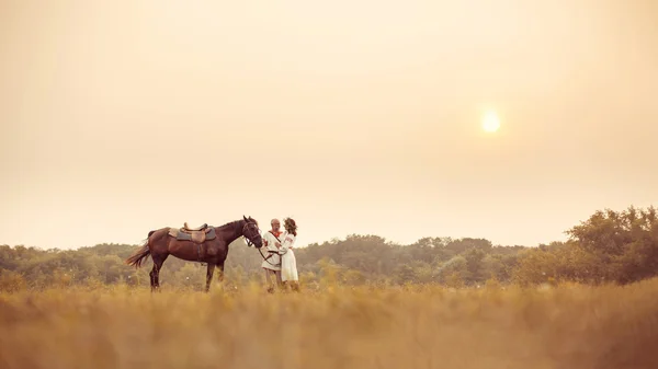 Mature man and woman in ethnic clothes are going to make a horse — Stock Photo, Image