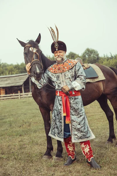 Король, одягнений у середньовічний костюм, погладжує свого коня на руці — стокове фото