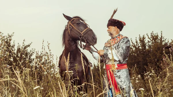 Král oblečený ve středověkých kostýmech se chystá vytáhnout svého koně na — Stock fotografie