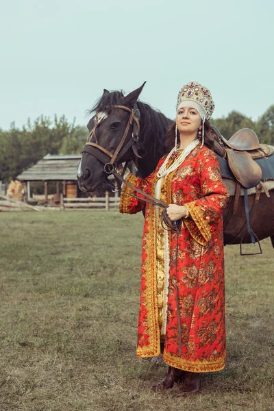 Noblesse médiévale en robe rouge et bijoux va à un cheval — Photo