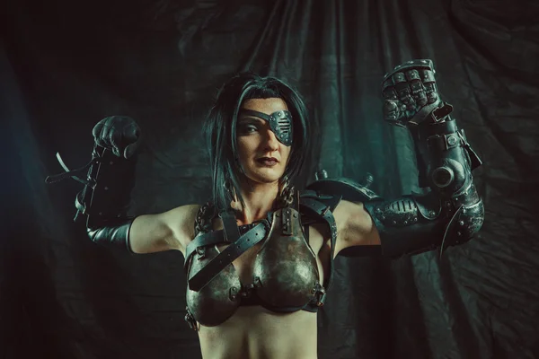 Powerful one-eyed steam punk woman in metal lingerie is showing us her iron muscles. — Stock Photo, Image