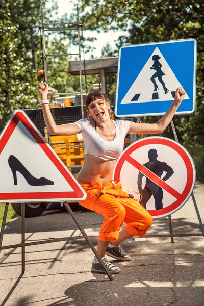 橙色工作服的女人越来越多的"无人"标志的道路上 — 图库照片