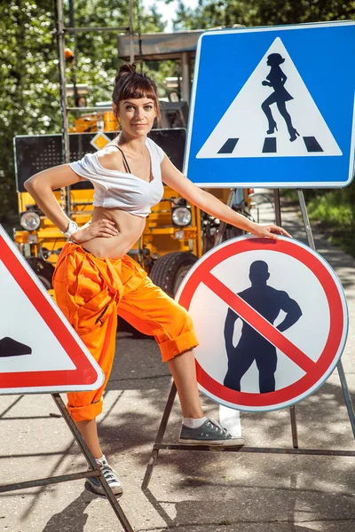 Mulher de macacão laranja está montando sinais "No Men" na estrada — Fotografia de Stock